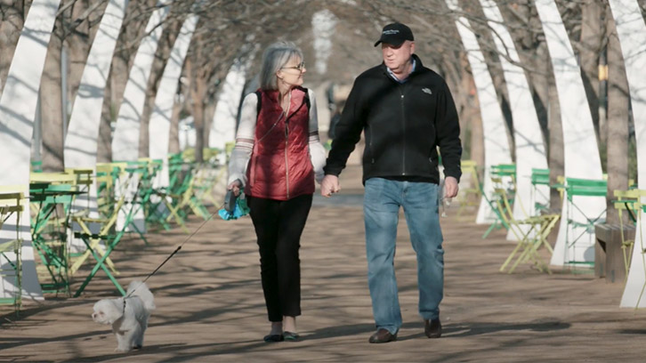 Woman-and-man-walking-in-the-park-with-their-dog